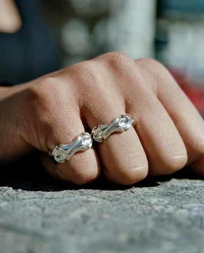 Close-up of a hand wearing two silver rings on a blurred background