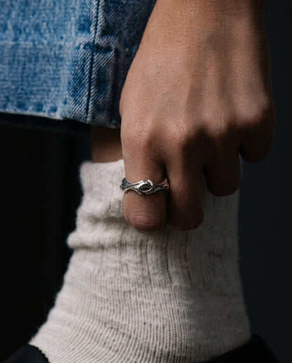 Close-up of a hand wearing a silver ring with a dark background