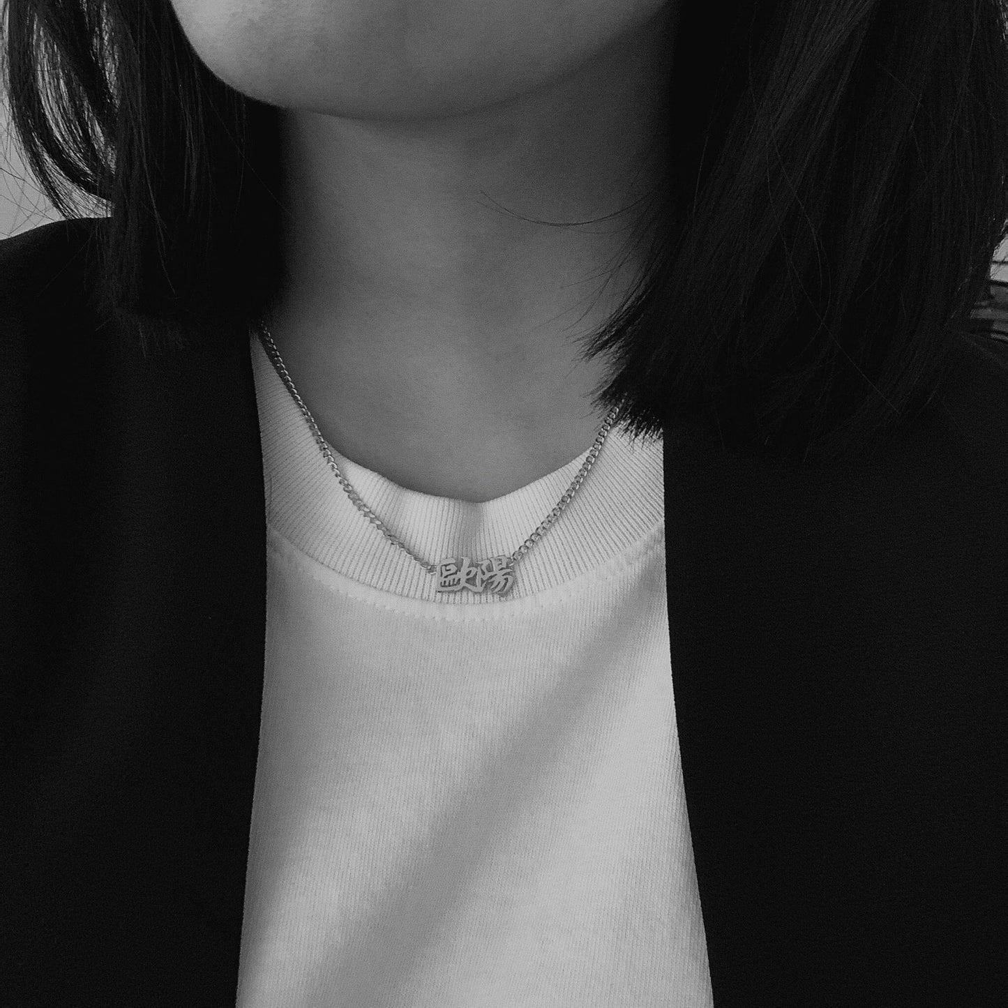 Person wearing a necklace with a small hanzi chinese pendant